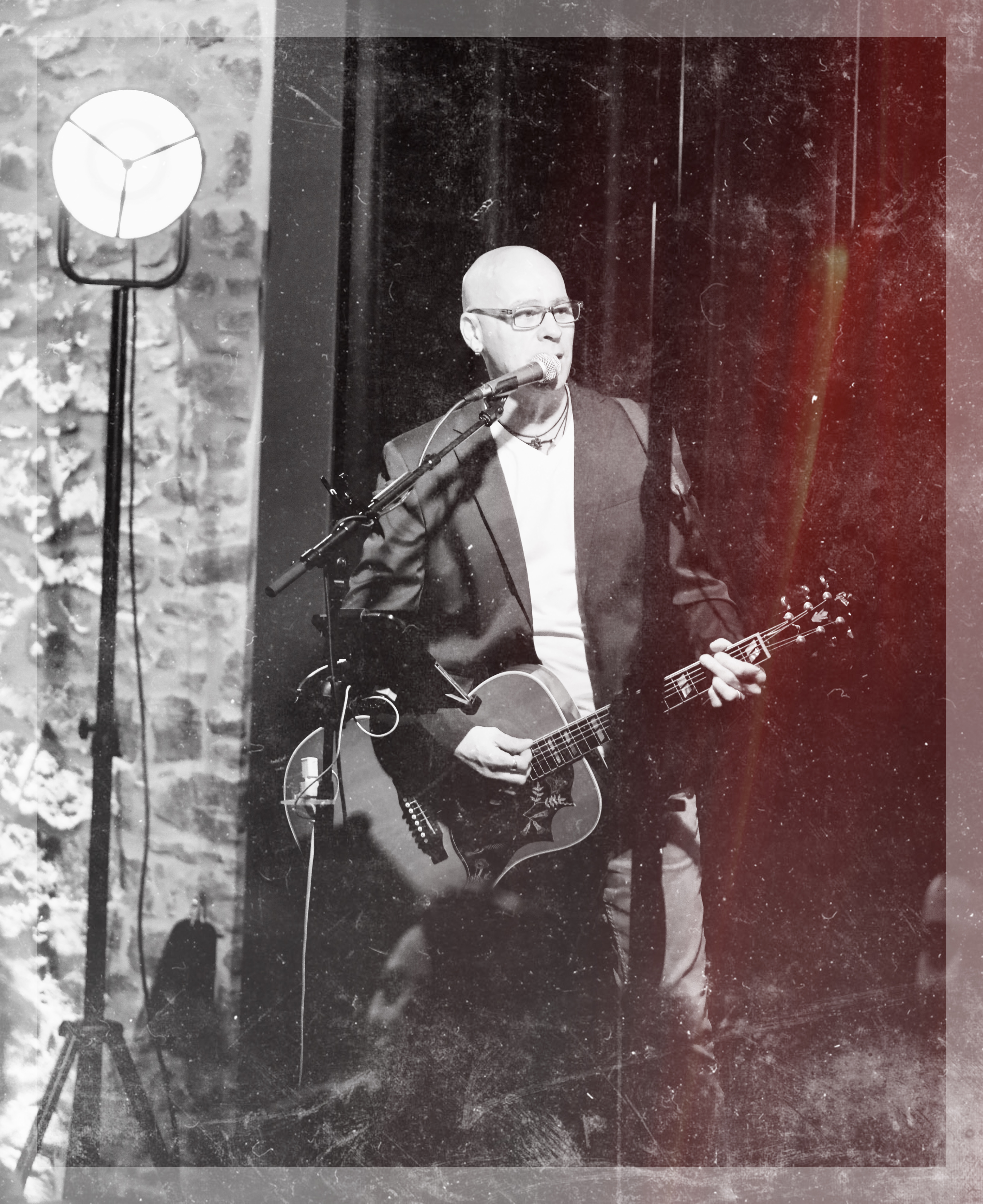 photo en noir et blanc de Nicolas BRAVIN chantant et jouant de la guitare 